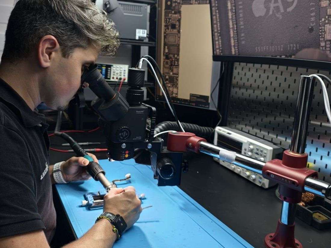 Javi Lima haciendo microsoldadura en la placa de un móvil con el microscopio del taller