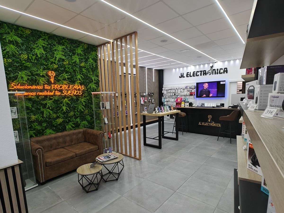 Interior de la tienda JL Electrónica con la zona de espera, el neón, el mostrador y la exposición de accesorios